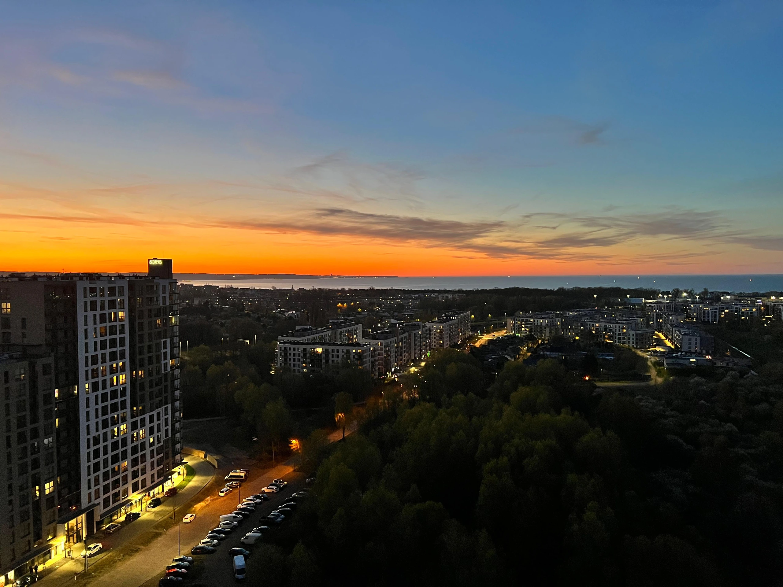 Panorama Letnicy o zachodzie słońca — morze, osiedle i światła miasta